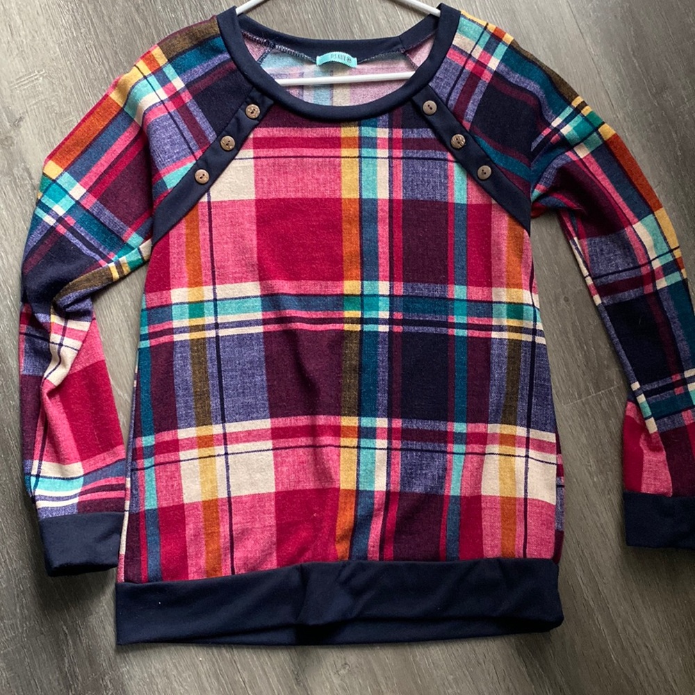 Long sleeved, plaid shirt with button detail.